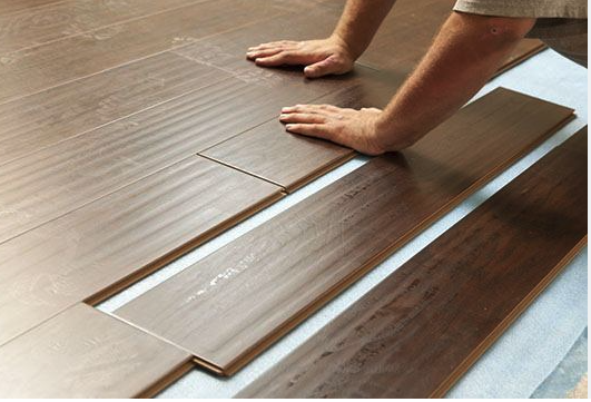 Person installing vinyl plank flooring in a rental unit to improve durability and tenant appeal.